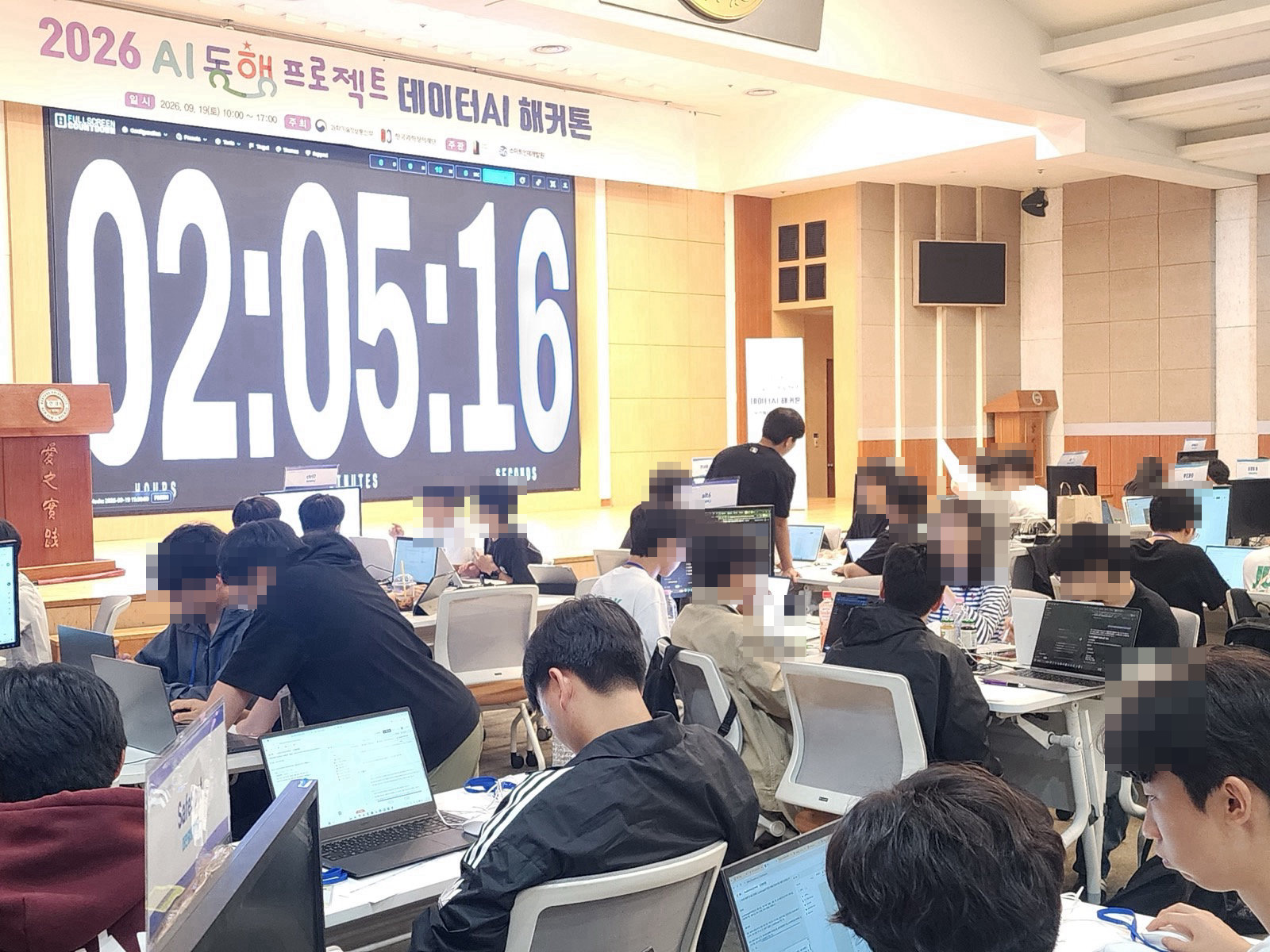 앞 화면에 남은 시간 타이머가 떠 있고 학생 팀들이 노트북으로 앱을 만드는 모습