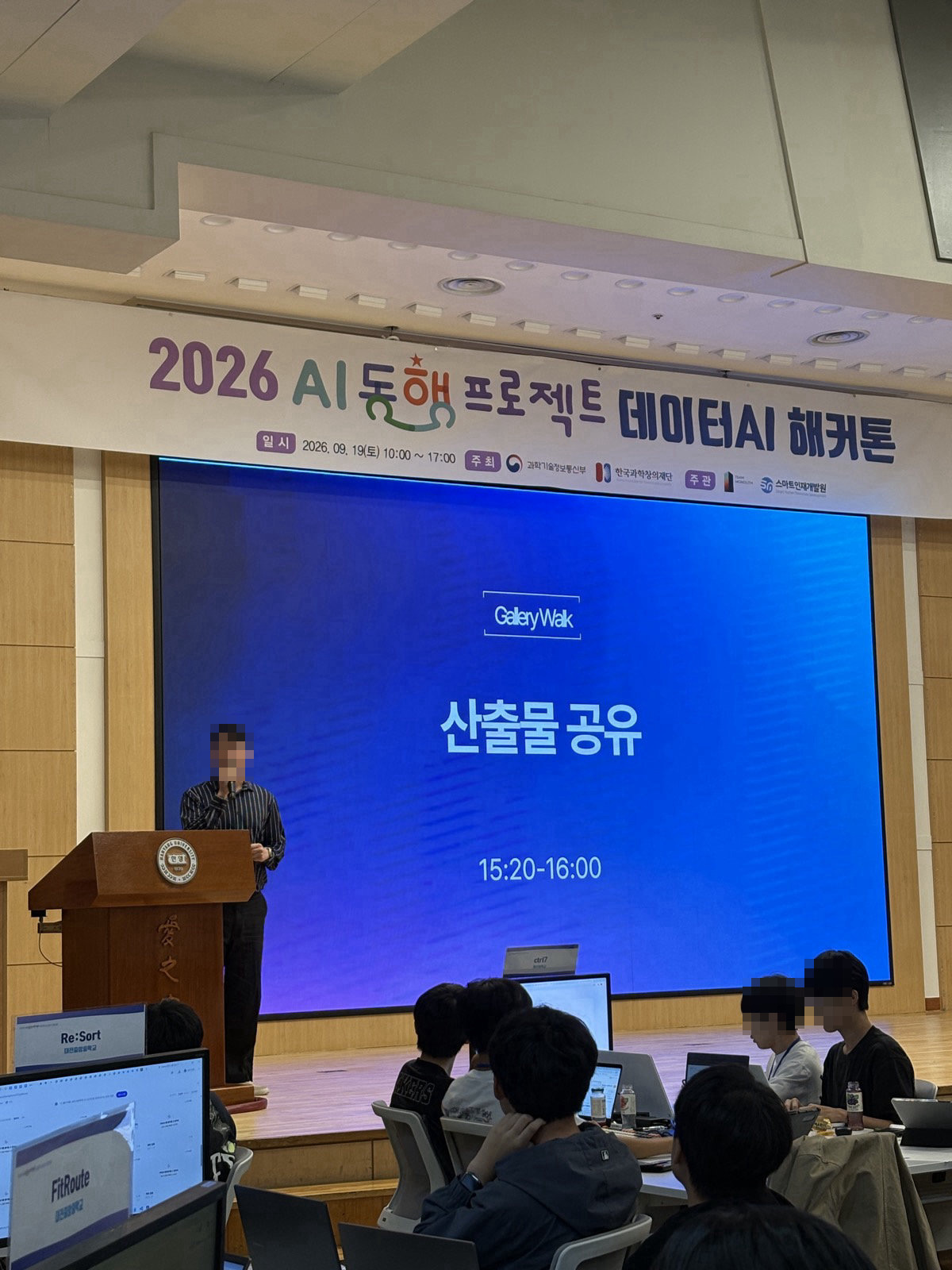진행자가 무대에서 ‘Gallery Walk 산출물 공유’ 화면을 띄우고 안내하는 모습