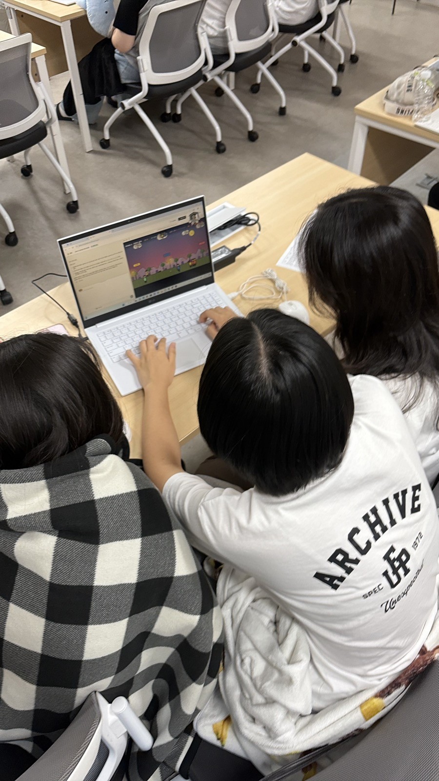 두 학생이 노트북으로 함께 게임 앱을 만드는 모습