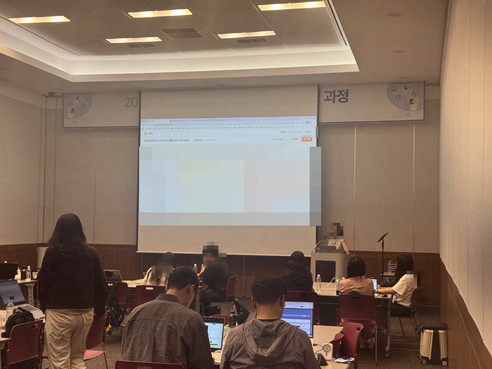 연수장에서 참가 교사들이 스크린의 짓다 화면을 보며 각자 노트북으로 작업하는 모습