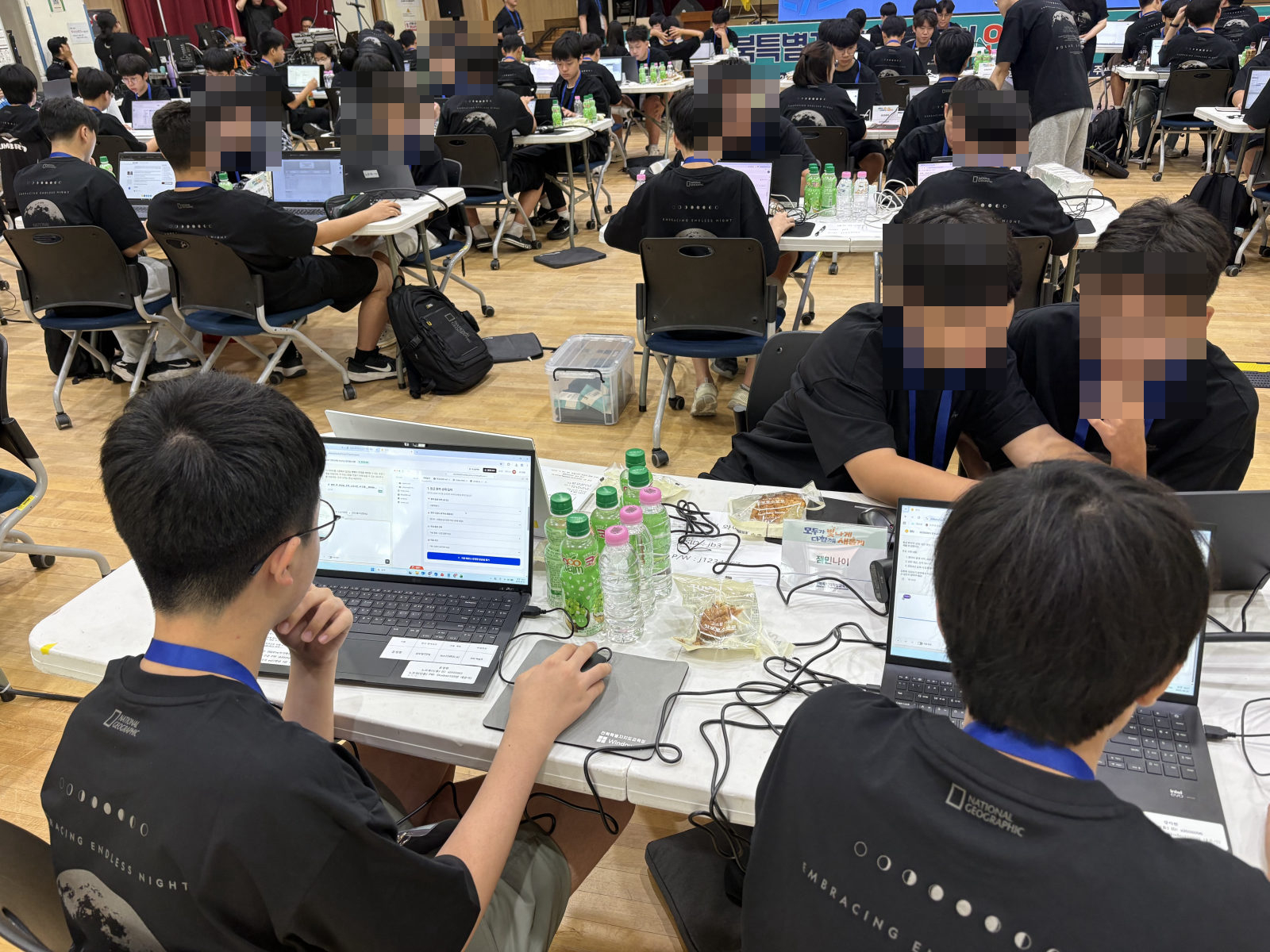 같은 테이블에 앉은 학생들이 노트북으로 팀별 앱을 개발하는 모습