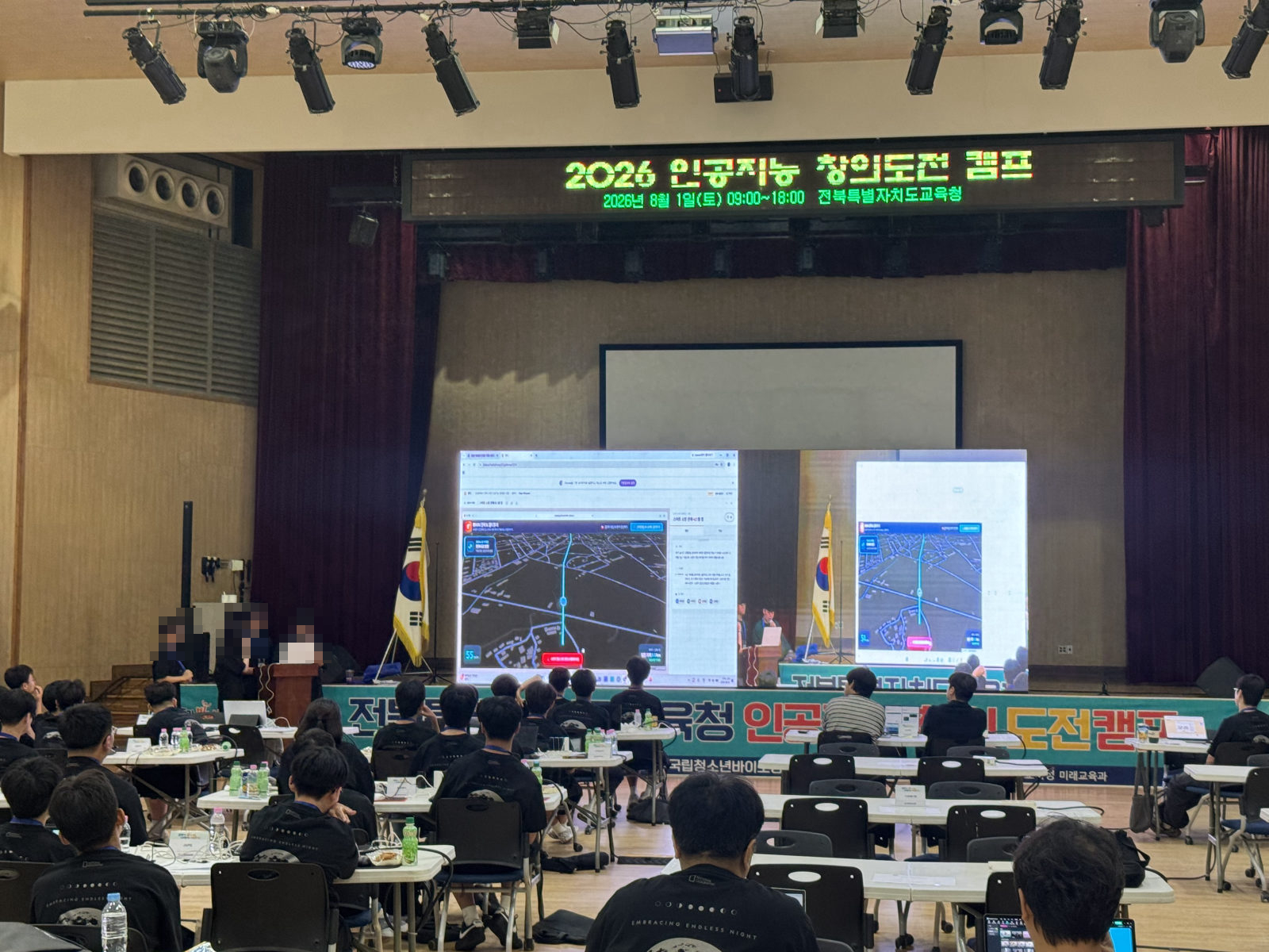 대강당 무대 화면에 학생 팀이 만든 앱을 띄우고 발표하는 모습